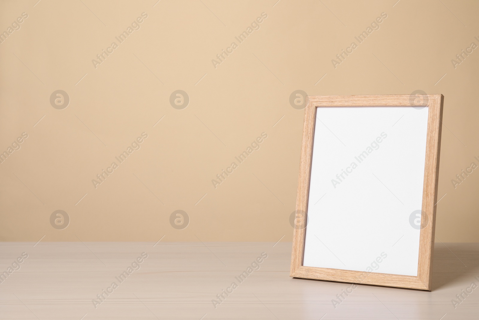 Photo of Empty square frame on white wooden table, space for text