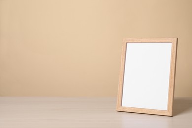 Photo of Empty square frame on white wooden table, space for text