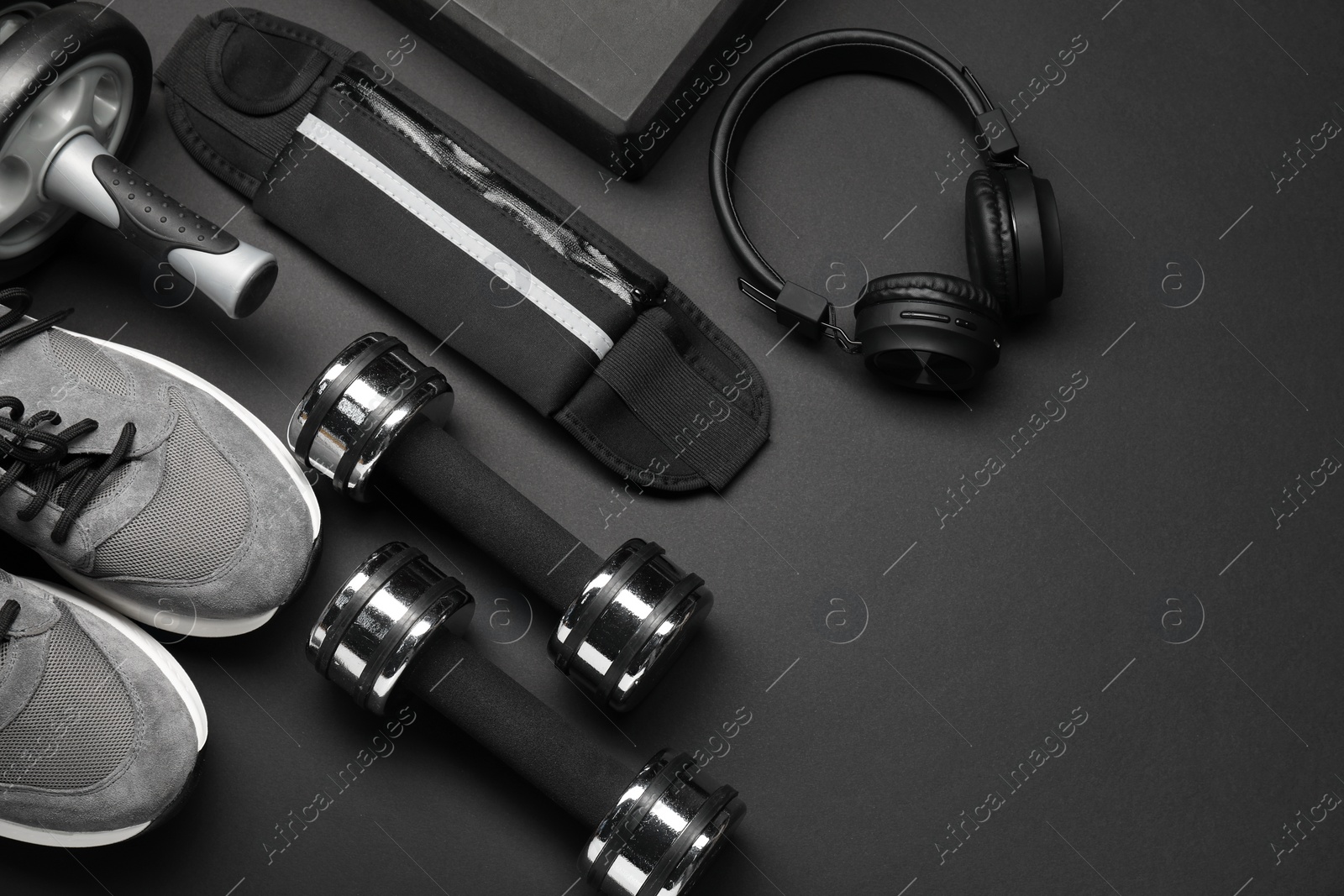 Photo of Sports equipment, headphones and sneakers on black background, flat lay. Space for text