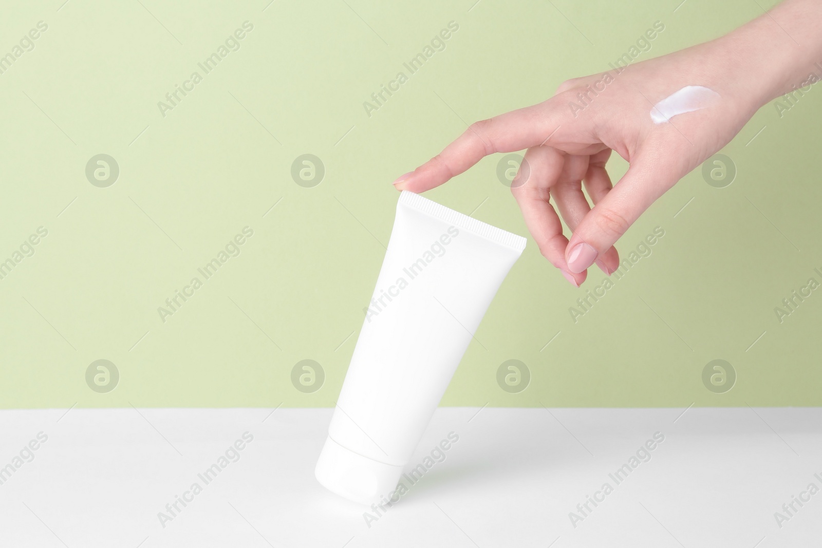 Photo of Woman with tube of cream on color background, closeup