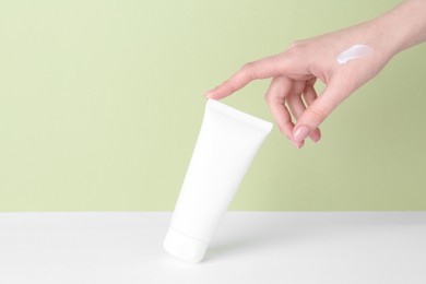 Photo of Woman with tube of cream on color background, closeup