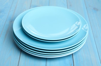 Photo of Empty clean ceramic dishware on turquoise wooden table, closeup