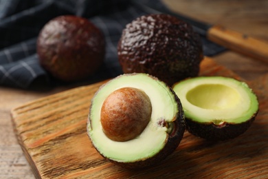 Photo of Halves of delicious ripe avocado on wooden board