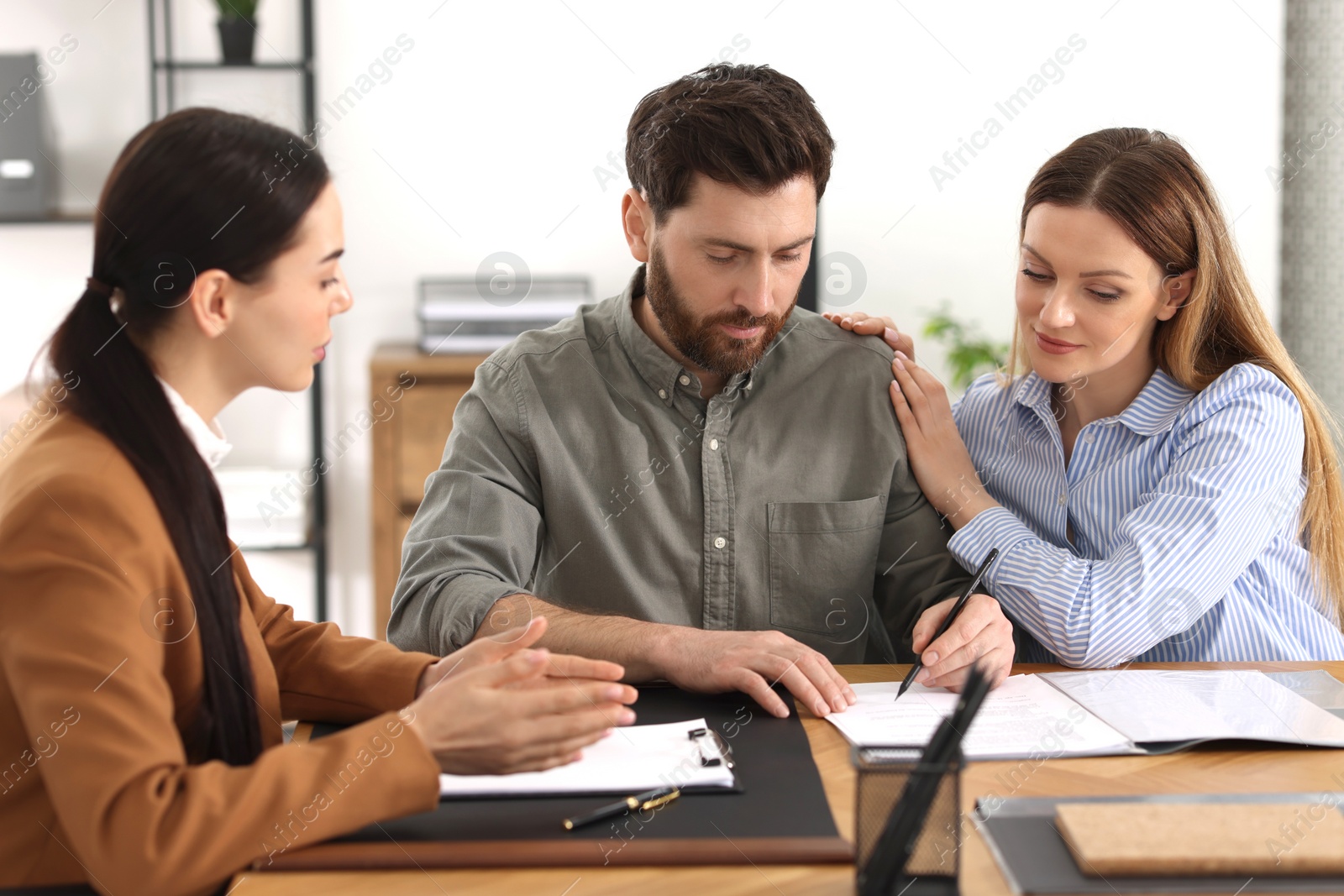 Photo of Couple signing document while having meeting with lawyer in office