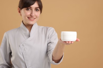 Cosmetologist with cosmetic product on beige background, selective focus