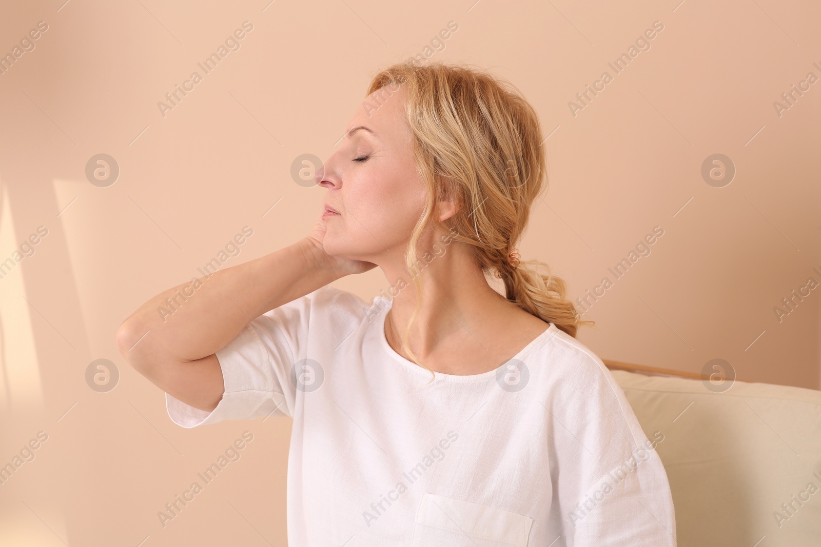 Photo of Woman suffering from hormonal disorders near beige wall indoors