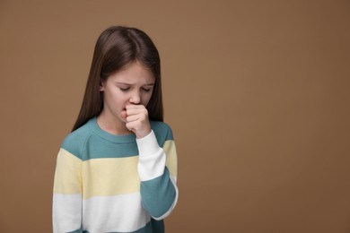 Photo of Sick girl coughing on brown background, space for text