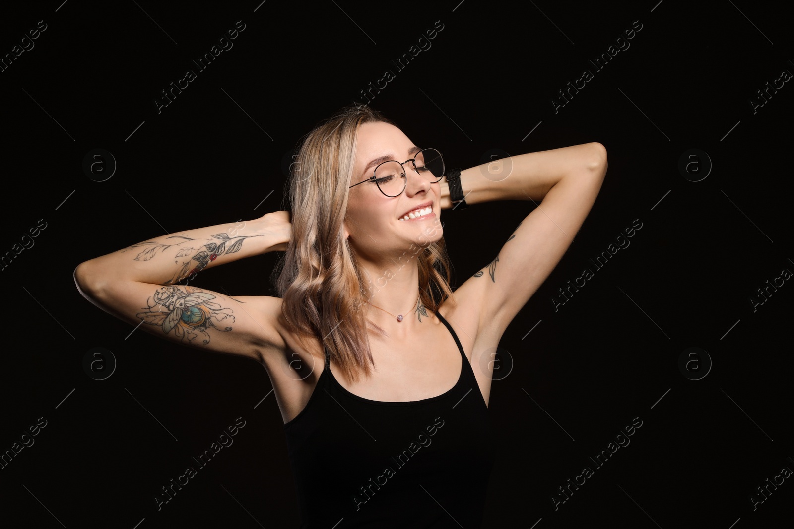 Photo of Beautiful woman with tattoos on body against black background