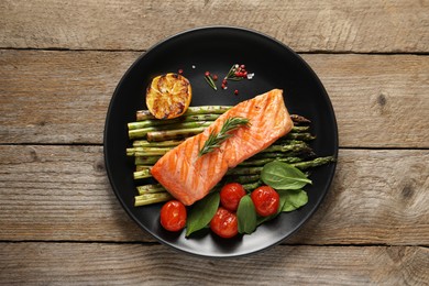 Photo of Tasty grilled salmon with tomatoes, asparagus and spices on wooden table, top view