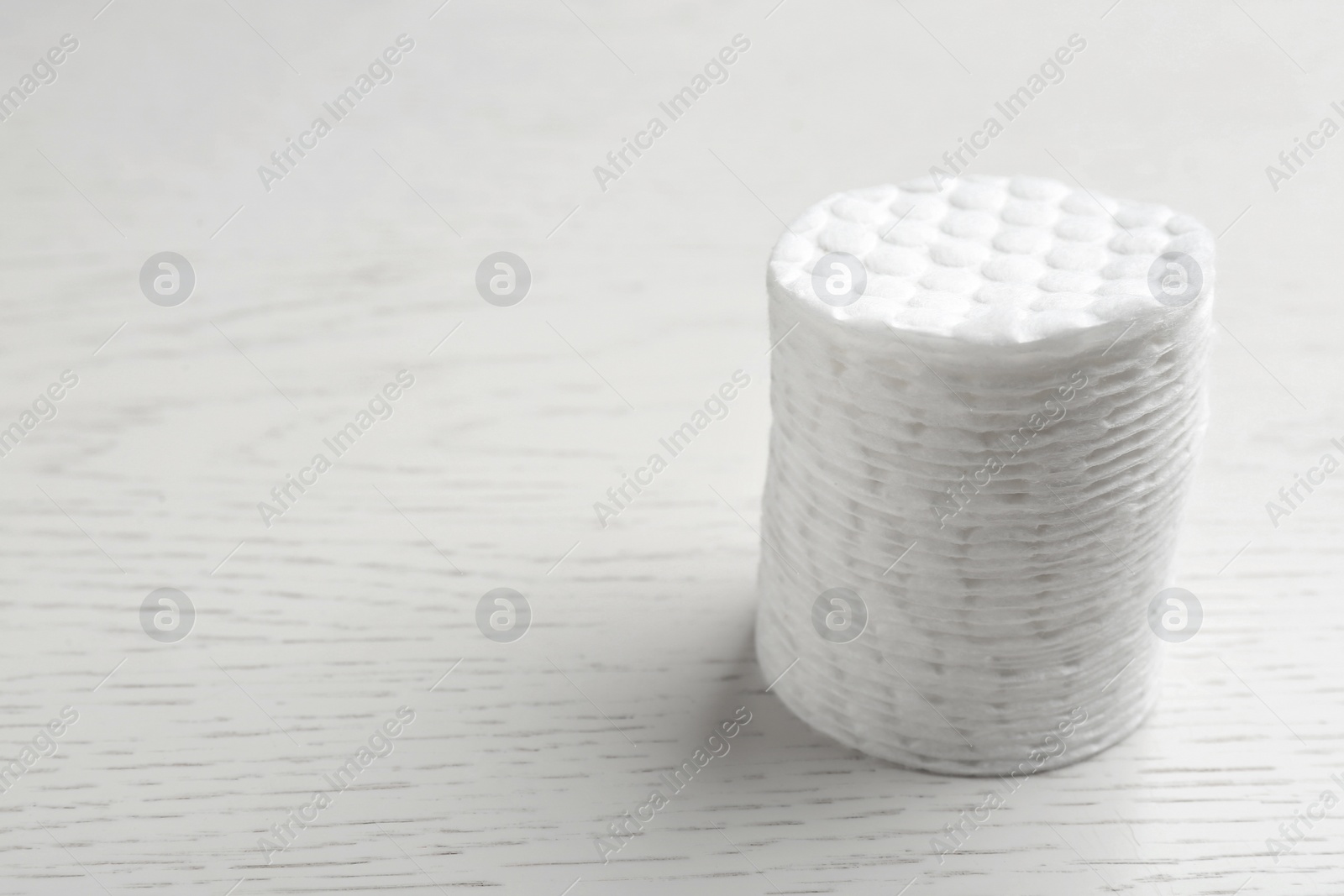 Photo of Stack of cotton pads on white wooden background. Space for text