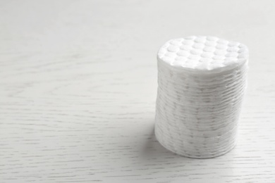 Stack of cotton pads on white wooden background. Space for text