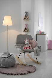 Photo of Cozy baby room interior with comfortable rocking chair