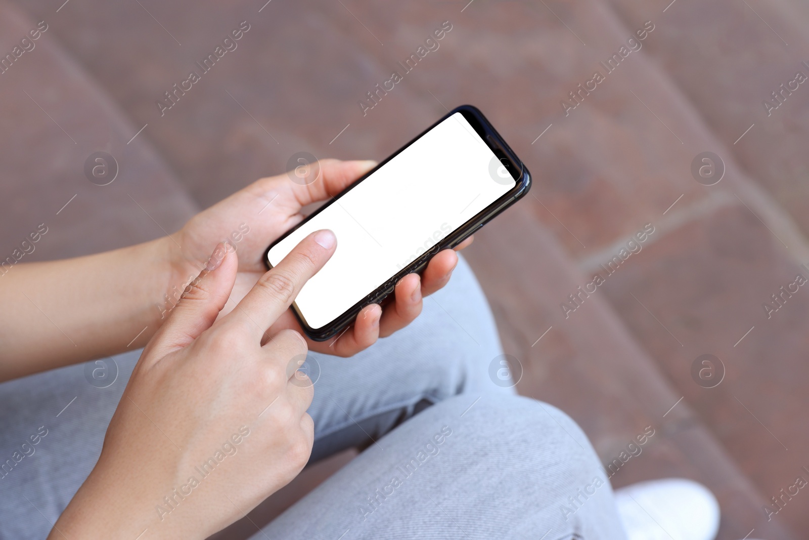 Photo of Closeup view of woman with smartphone sitting outdoors