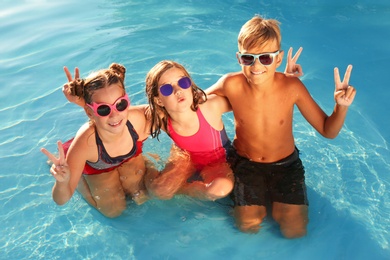 Happy children with sunglasses in swimming pool