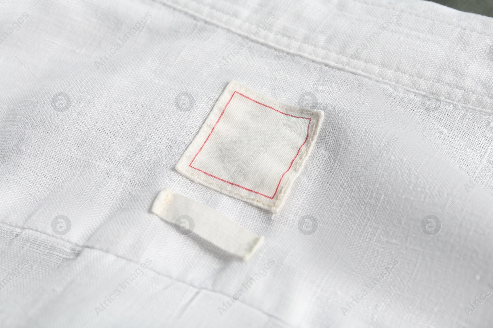 Photo of Blank clothing labels on white shirt, closeup