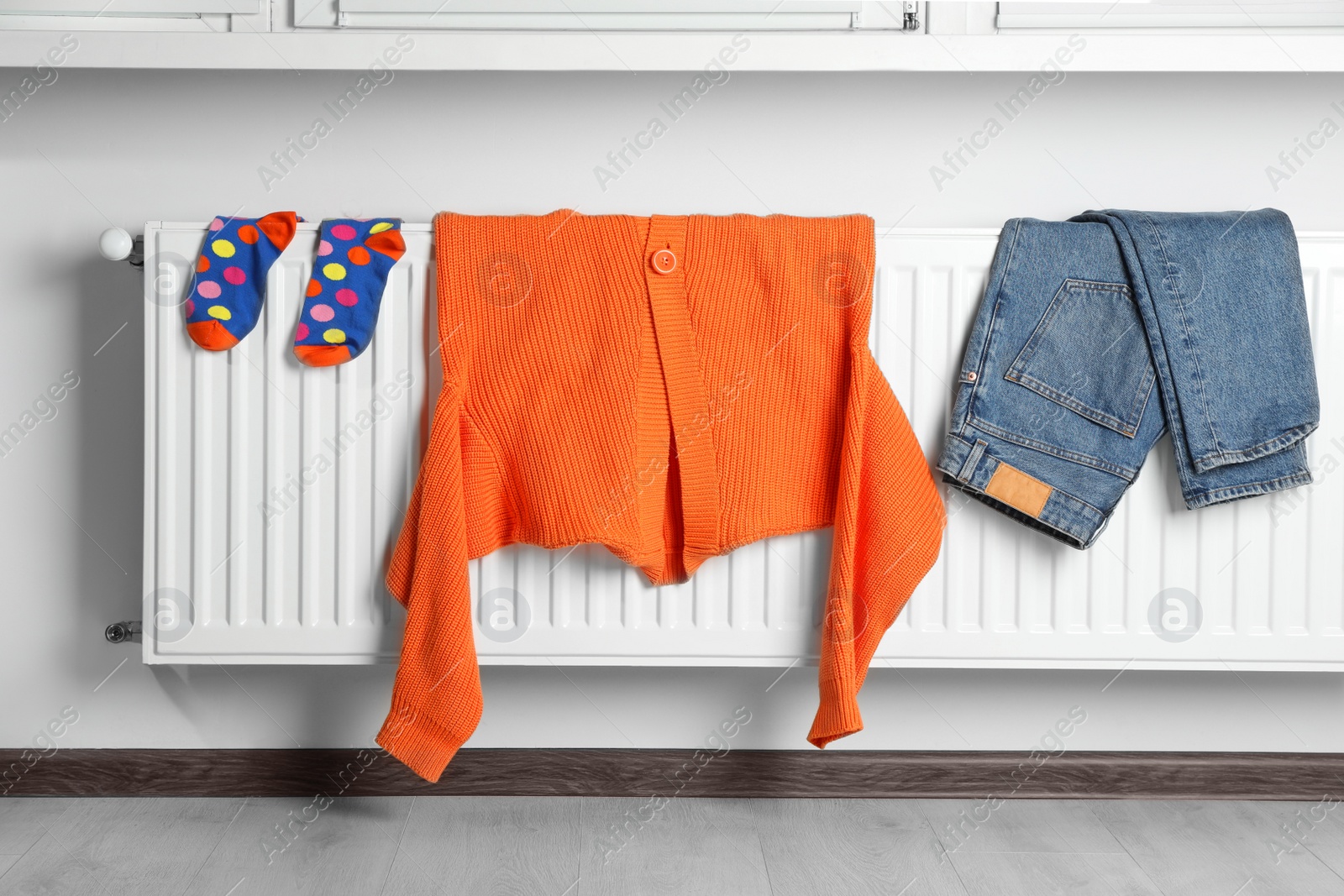 Photo of Clean clothes hanging on white radiator in room