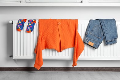 Photo of Clean clothes hanging on white radiator in room