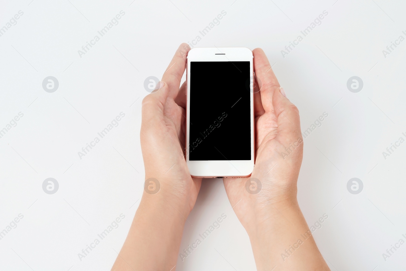 Photo of Young woman holding mobile phone with blank screen in hands on white background