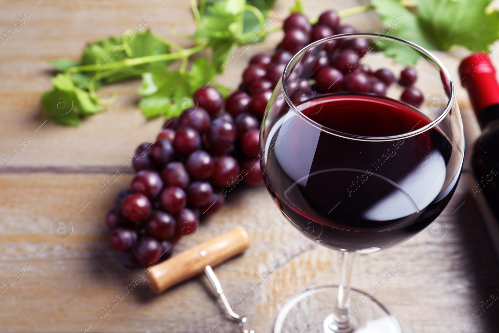 Photo of Fresh ripe juicy grapes and glass of wine on wooden table, closeup