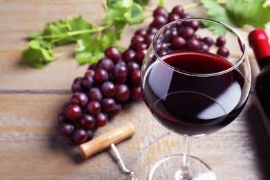 Photo of Fresh ripe juicy grapes and glass of wine on wooden table, closeup