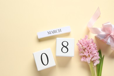 International Women's day - 8th of March. Gift box, wooden block calendar and beautiful flowers on beige background, flat lay