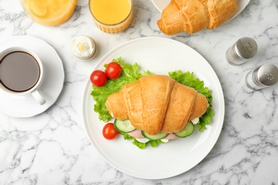 Photo of Tasty croissant sandwich with sausage on light background, top view