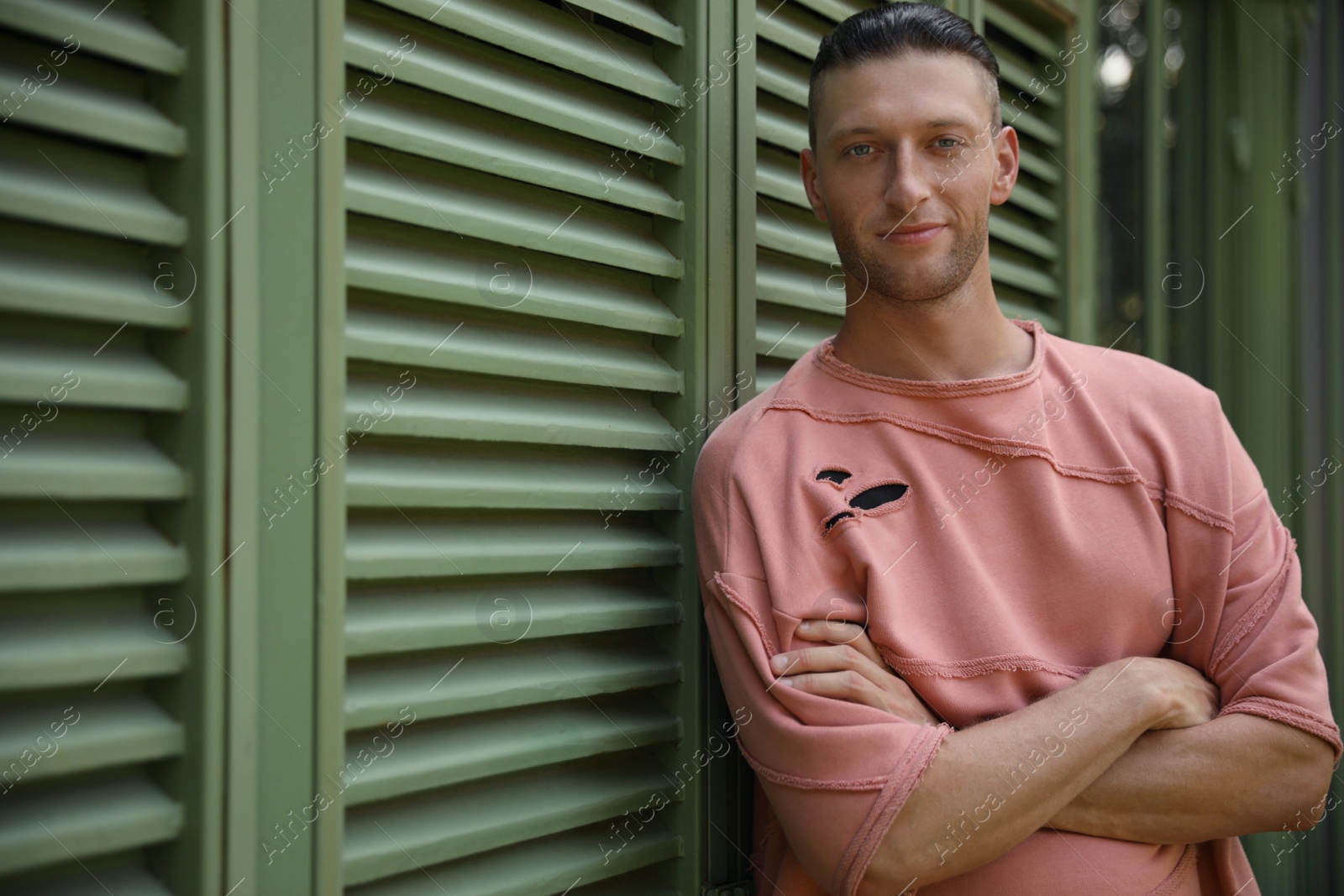 Photo of Handsome young man in stylish outfit near shutters outdoors. Space for text