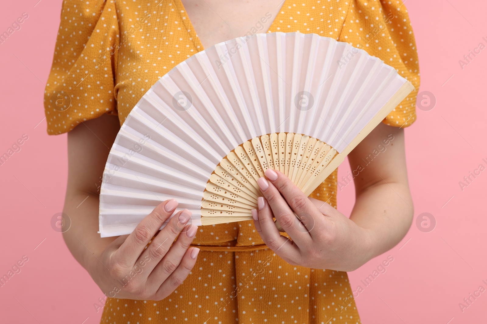 Photo of Woman with hand fan on pink background, closeup