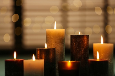 Beautiful burning candles table against festive lights