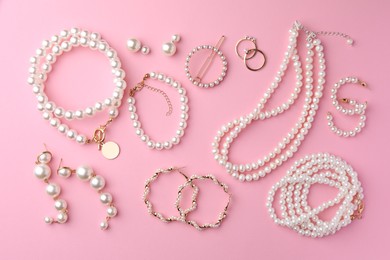 Elegant pearl jewelry on pink background, flat lay