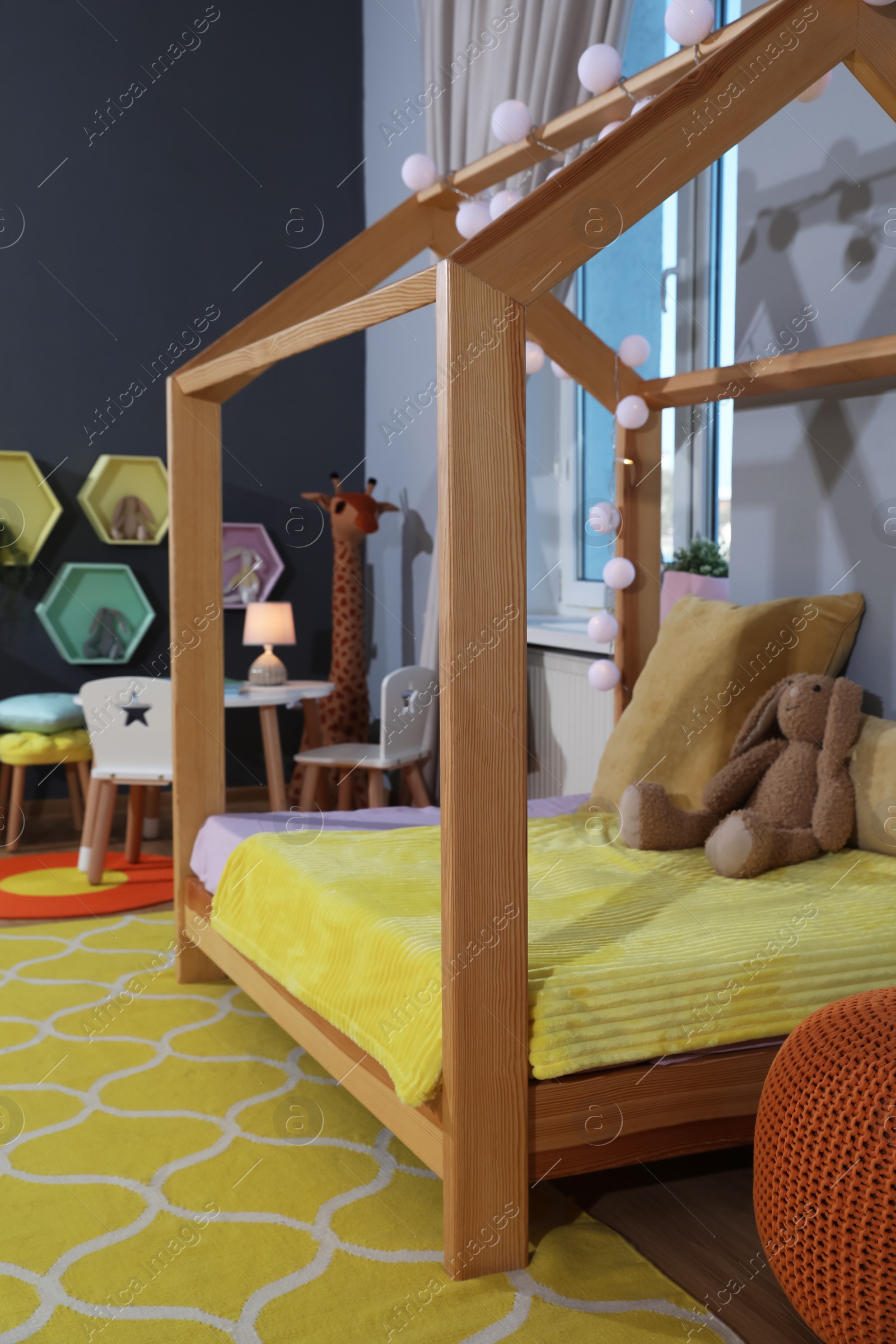 Photo of Stylish child room interior with comfortable house bed and toys