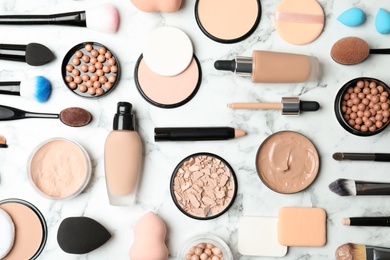 Flat lay composition with skin foundation, powder and beauty accessories on marble background