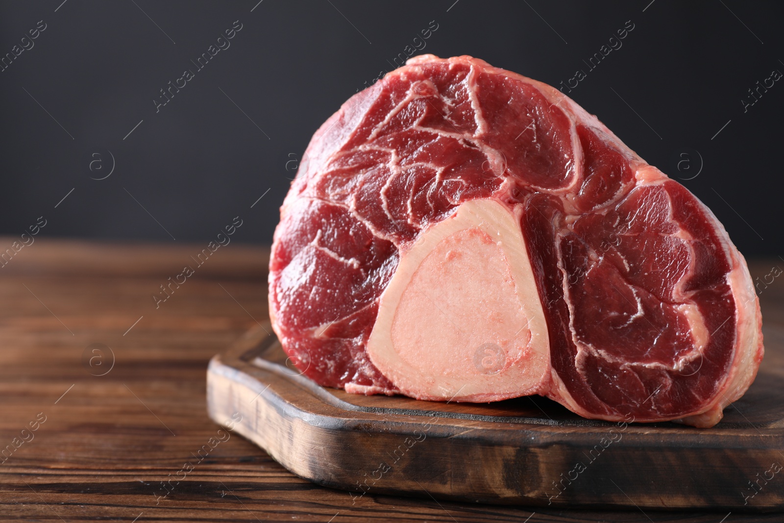 Photo of Piece of raw beef meat on wooden table, closeup. Space for text