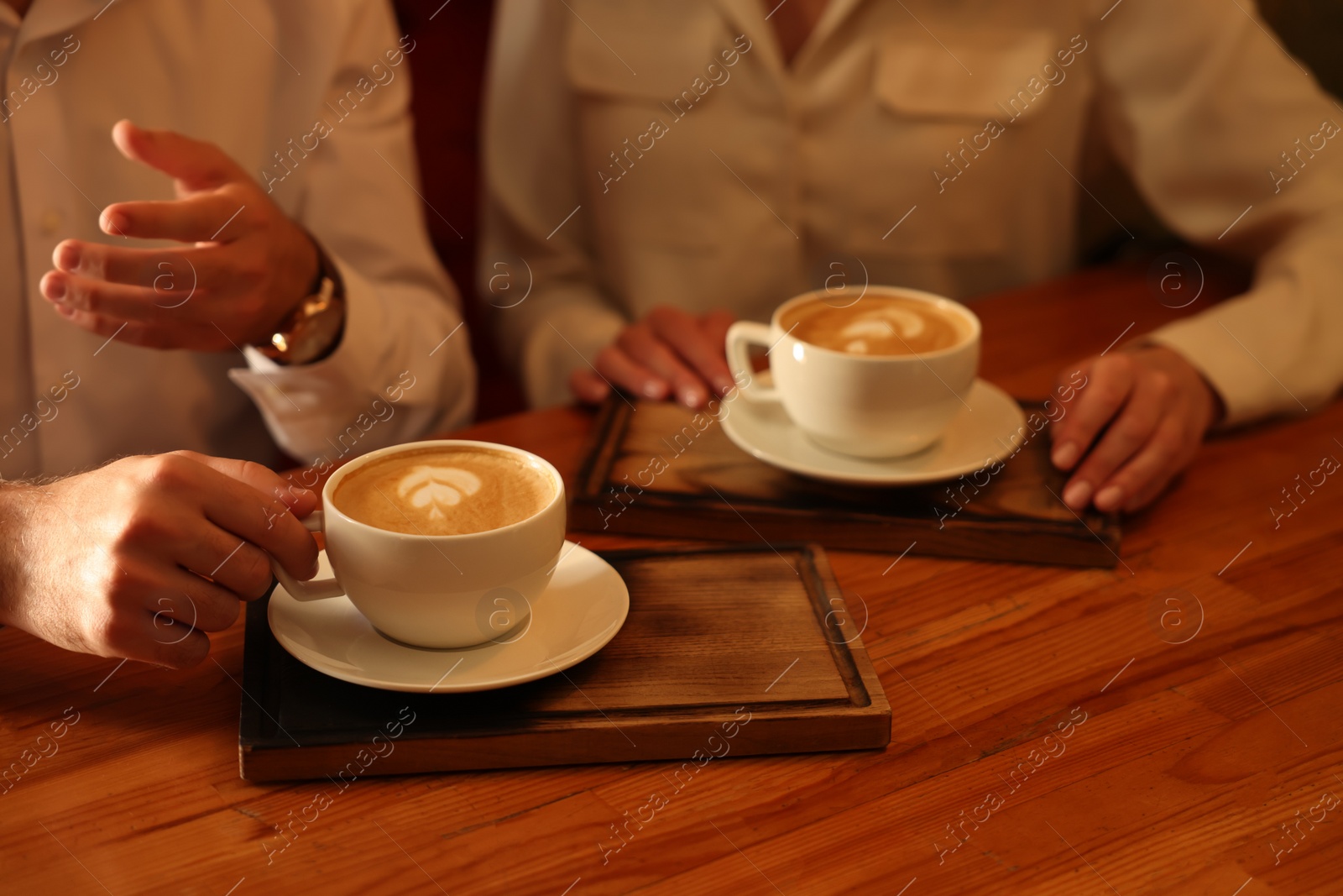 Photo of Couple with cups of aromatic coffee at wooden table, closeup