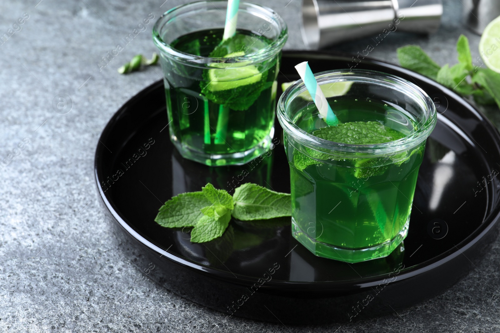 Photo of Delicious mint liqueur with green leaves and lime on grey table