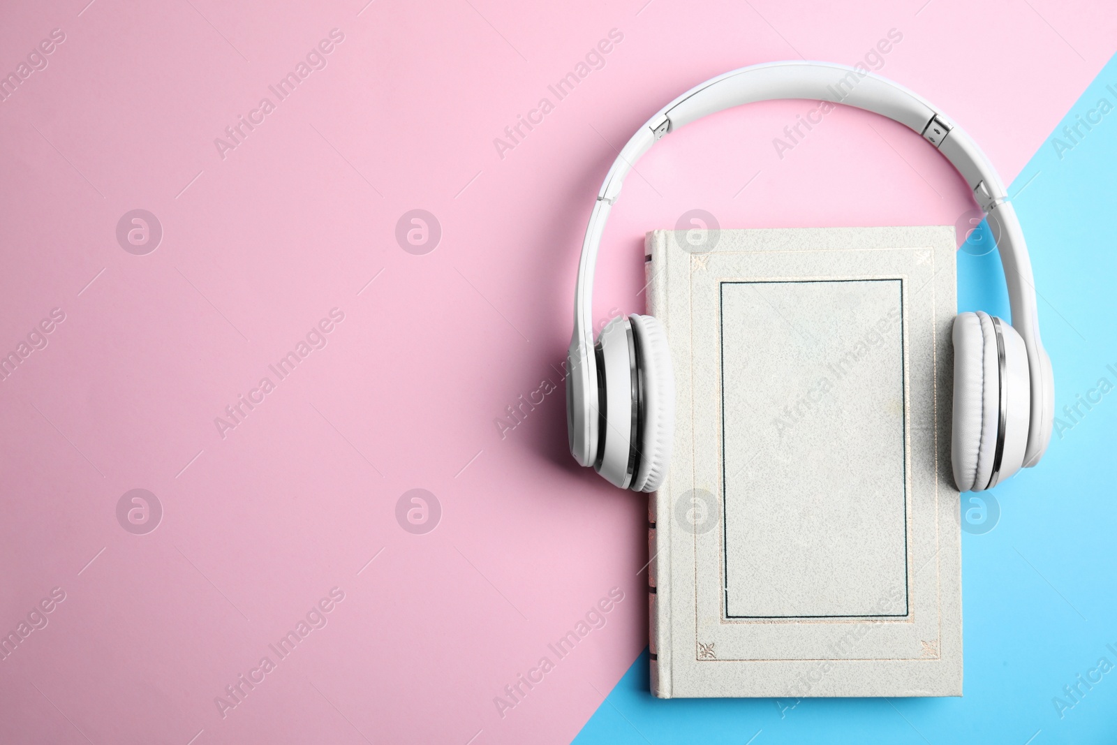 Photo of Book and modern headphones on color background, top view. Space for text