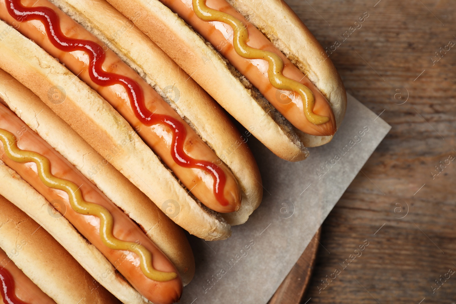 Photo of Tasty hot dogs on wooden table, top view