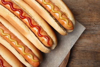 Photo of Tasty hot dogs on wooden table, top view
