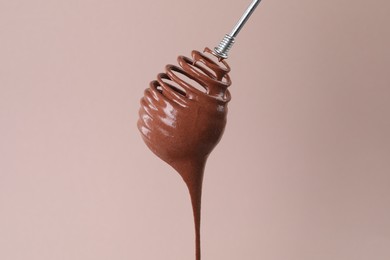 Photo of Chocolate cream flowing from whisk on light background