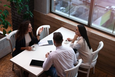 Group of coworkers having coffee break in cafe, above view