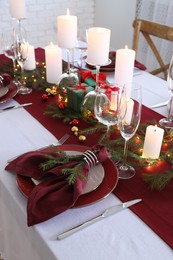 Christmas table setting with burning candles and festive decor