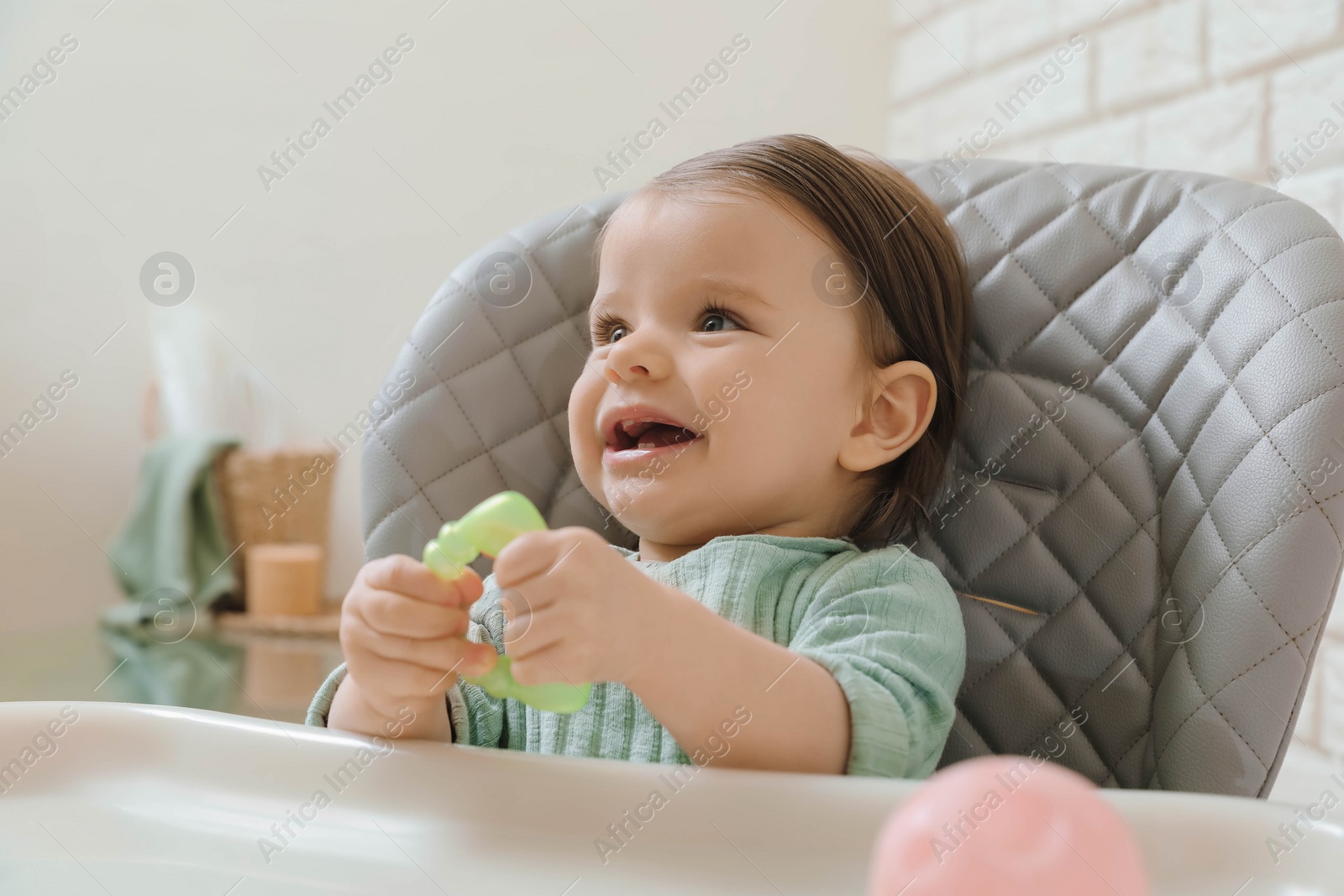 Photo of Cute little baby with teether in high chair indoors