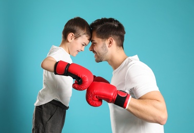 Dad and his son with boxing gloves on color background