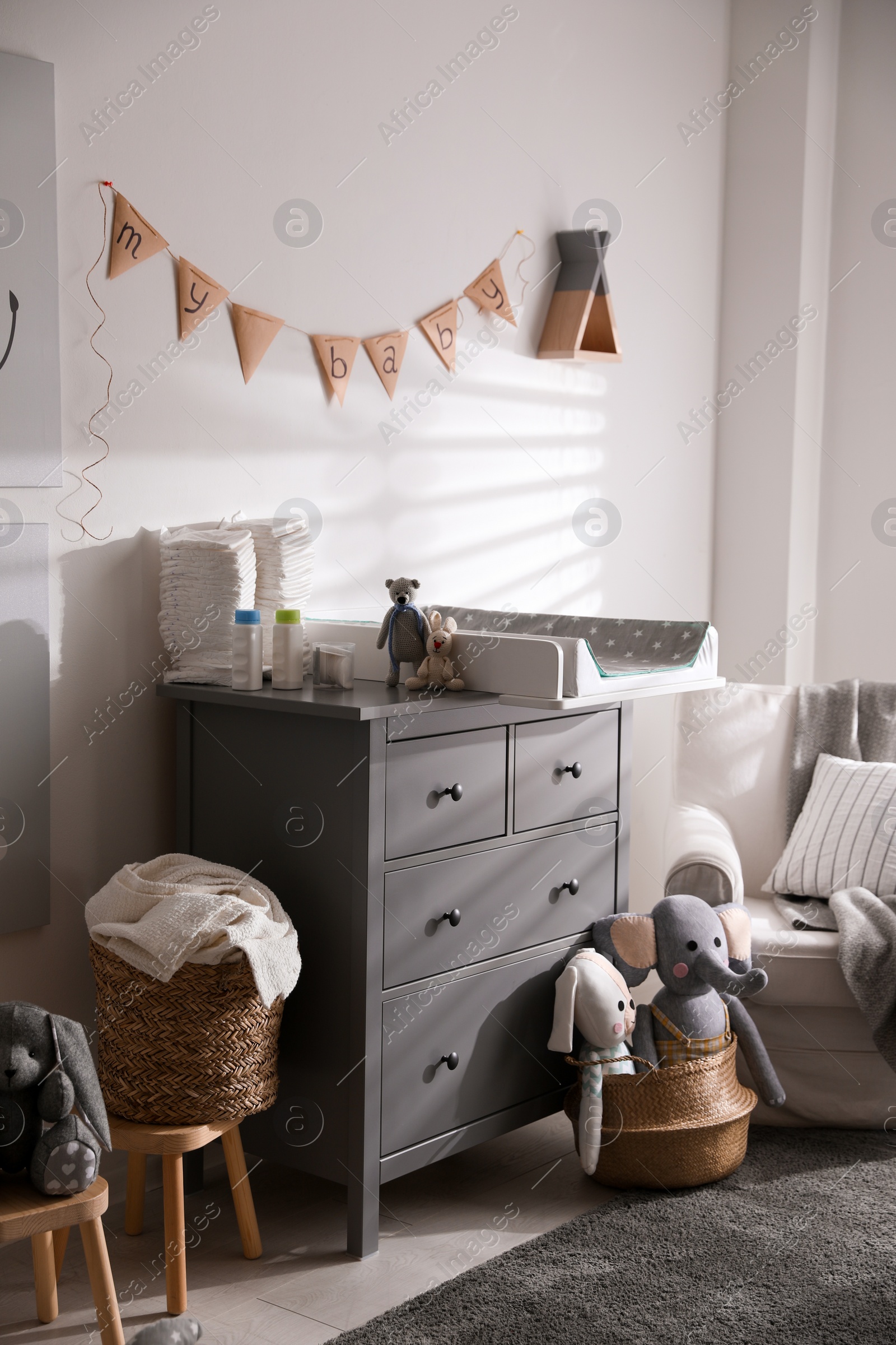 Photo of Chest of drawers with changing tray and pad in baby room. Interior design