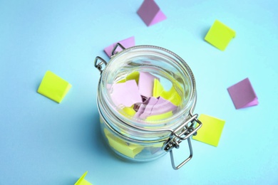 Photo of Glass jar and paper pieces for lottery on color background