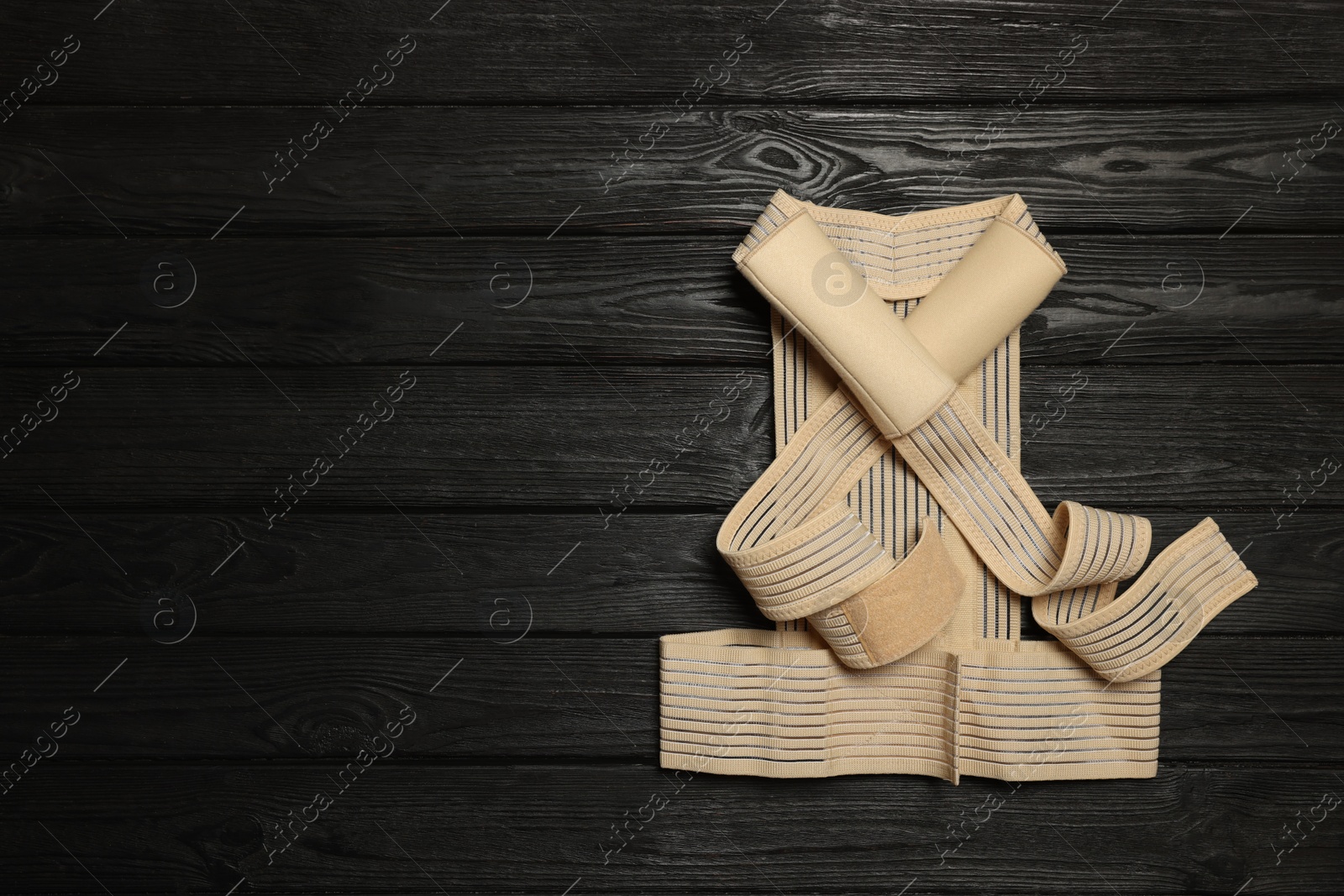 Photo of Beige posture corrector on black wooden table, top view. Space for text