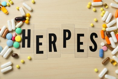 Photo of Flat lay composition with word Herpes and pills on wooden table