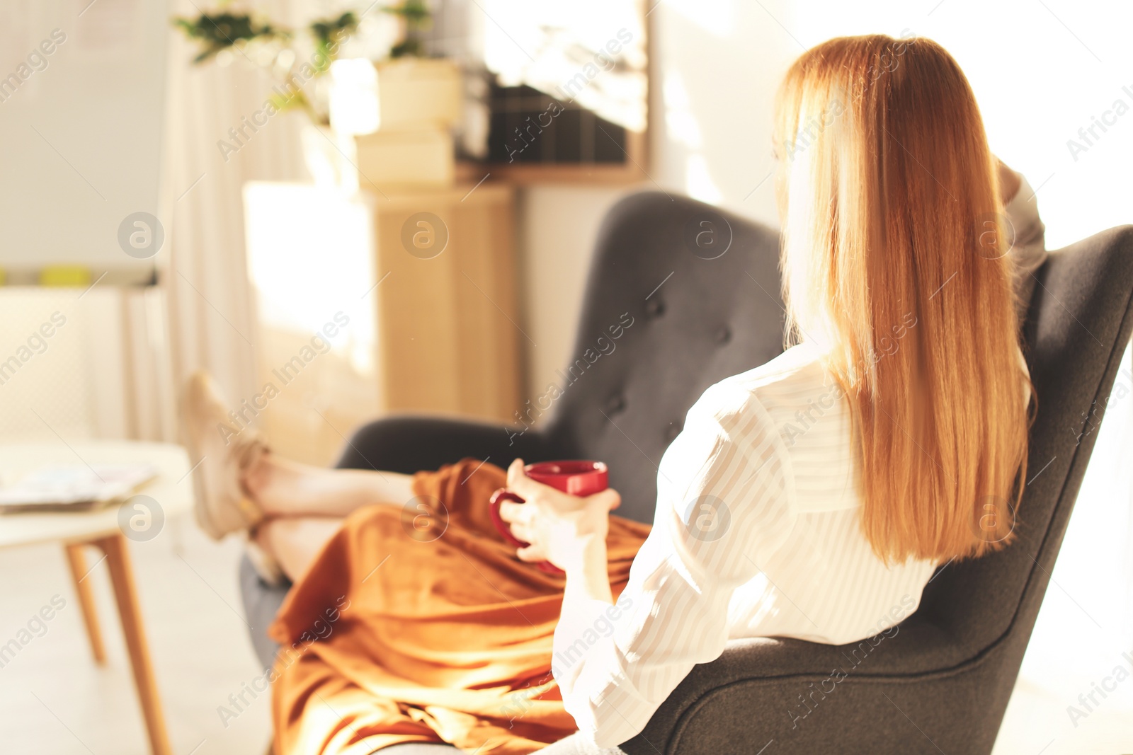 Photo of Young woman with cup of drink relaxing on couch at workplace