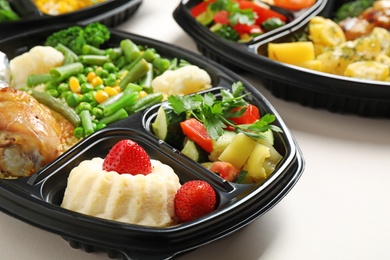 Photo of Lunchboxes with different meals on white table, closeup. Healthy food delivery