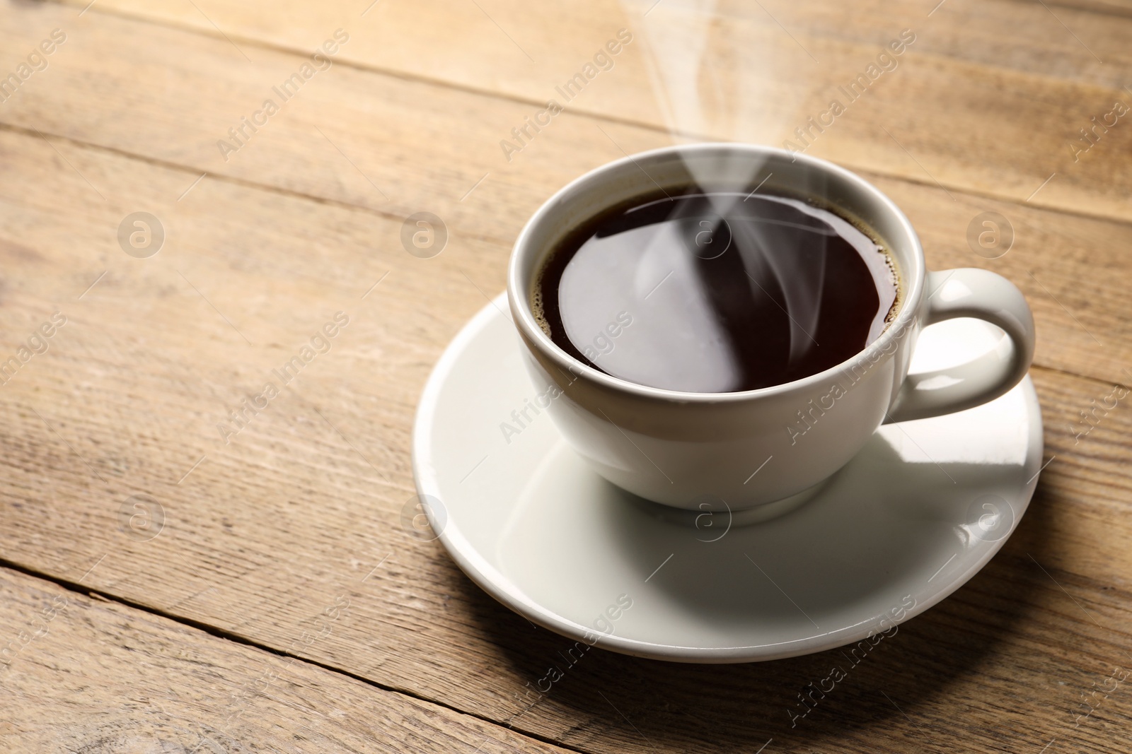 Image of Steaming coffee in cup on wooden table. Space for text